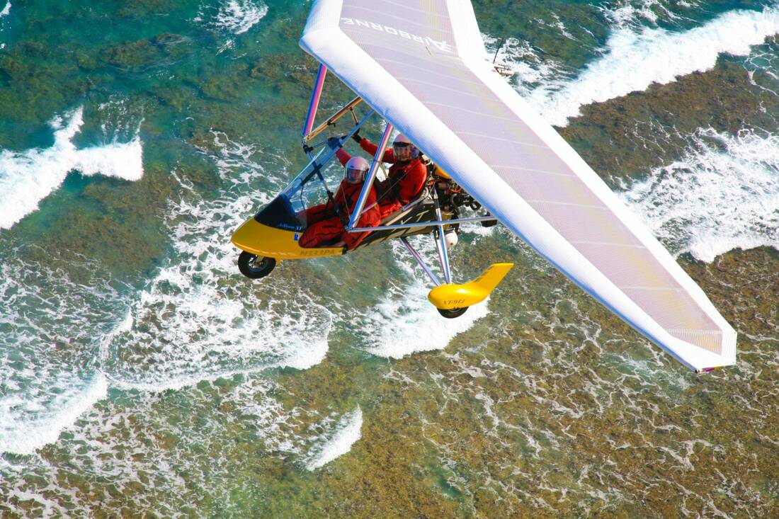A trike with two aboard, seen from above over reef and whitewater
