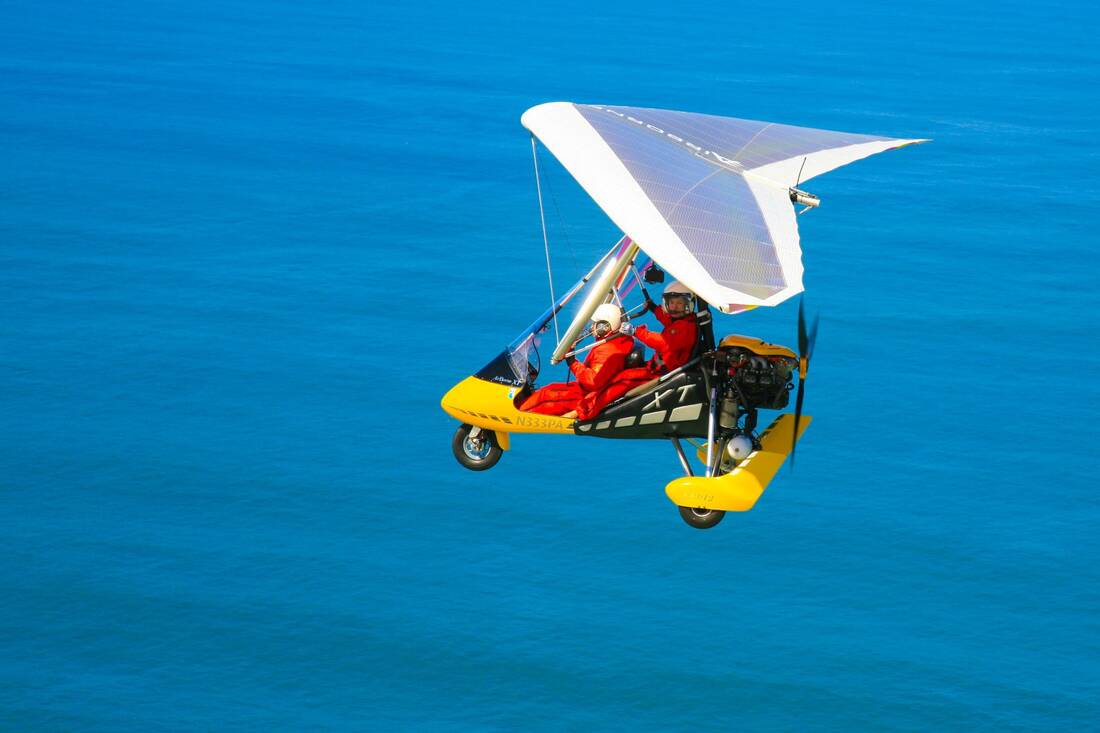 A white-winged trike over open blue water