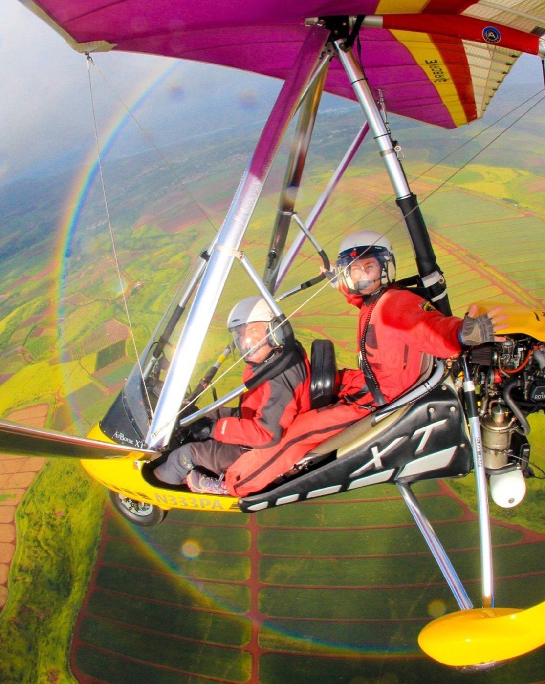 Two aboard beneath a magenta wing, a circular rainbow below