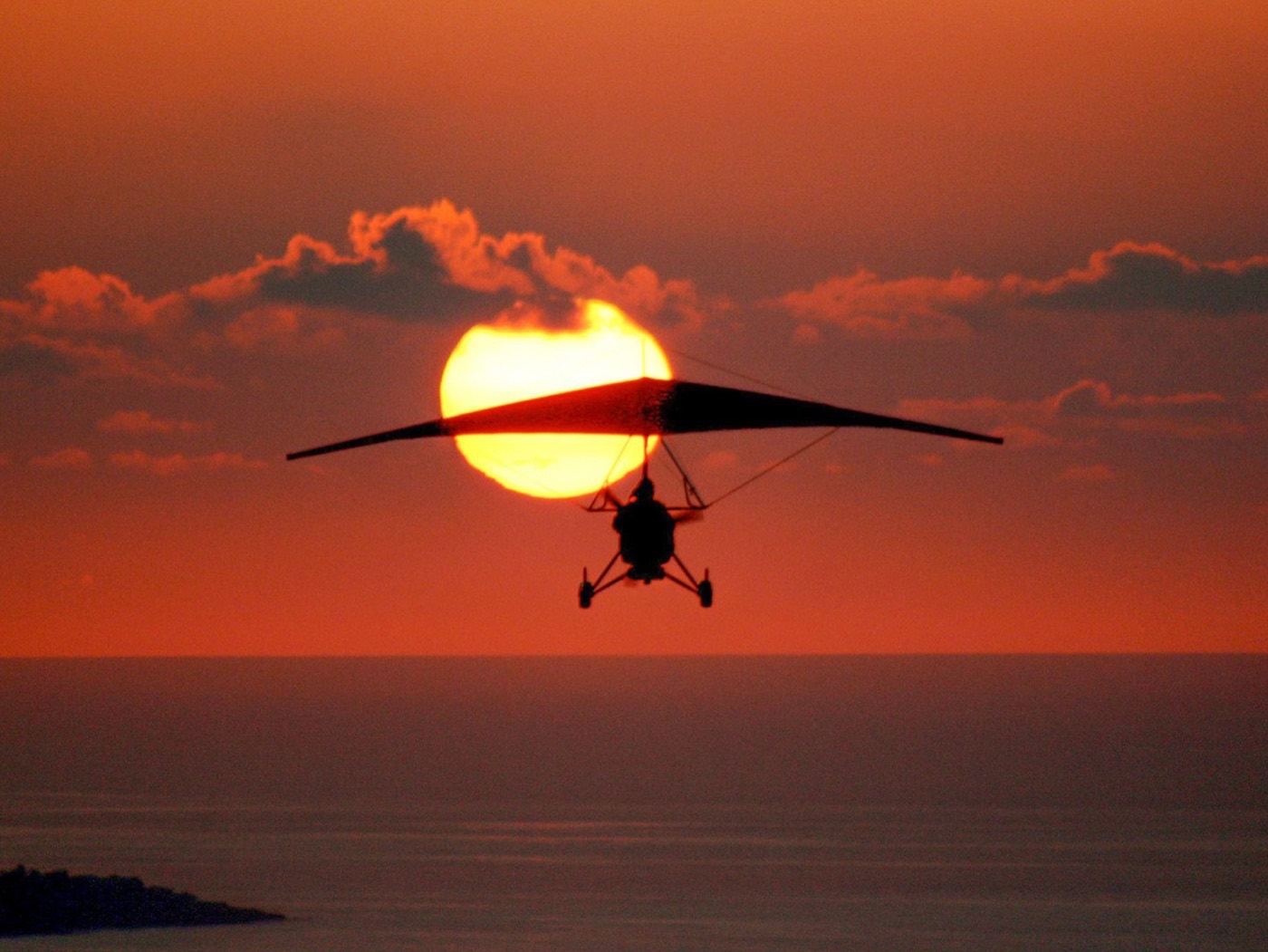 The trike silhouetted against the sun, low over the sea