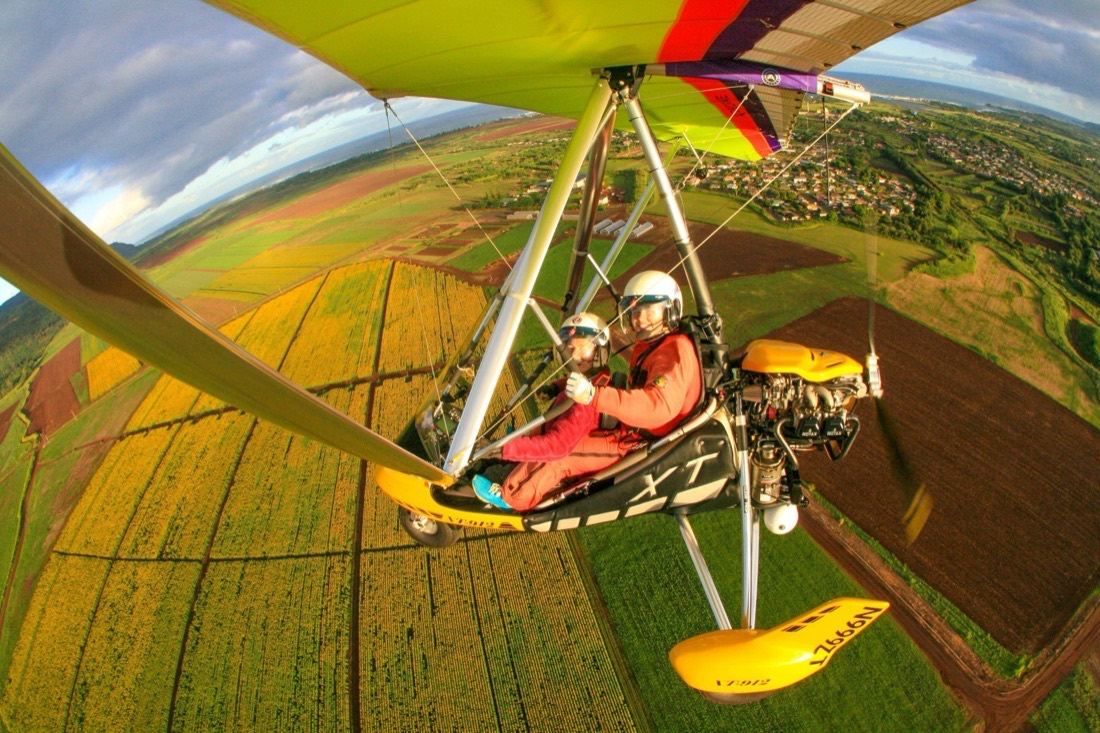 Two aboard the trike above fields, a town and the coastline